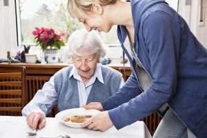 φροντιστής σερβίρει φαγητό σε ηλικιωμένη γυναίκα